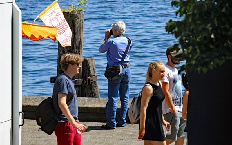 A man wearing blue shirt capturing views in Kieler Woche festival.