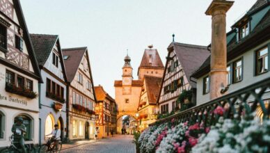 A man standing with his cycle infront of a building in Rothenburg in Germany