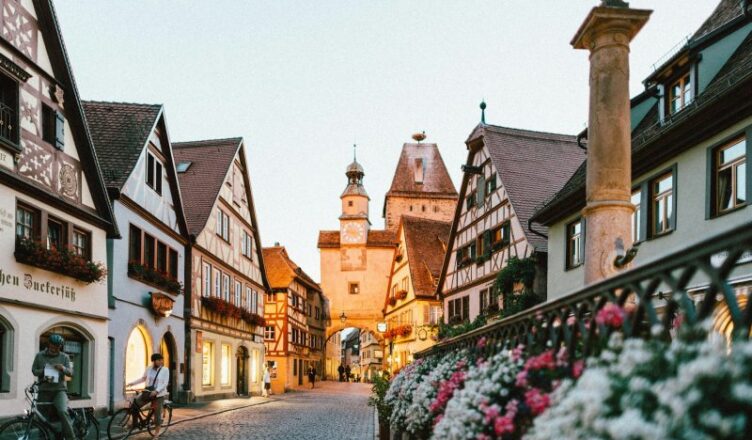 A man standing with his cycle infront of a building in Rothenburg in Germany